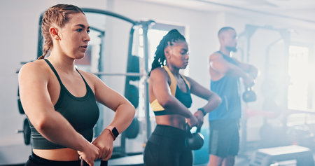Fitness, exercise and kettlebell with personal trainer, class and gym for training or workout routine. Weightlifting, goals and target with group of sports people in health club together for muscleの写真素材