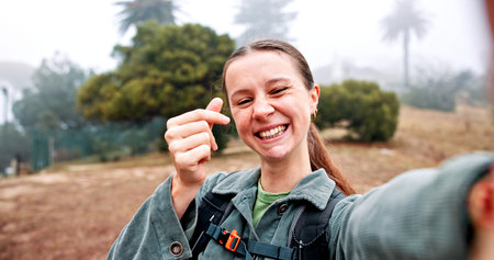 Hiking, selfie and finger hearts with woman in nature for social media, travel and adventure....