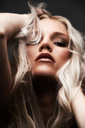 Portrait, woman and confident in studio with haircare, beauty and cosmetic with pride by gray background. Model, face and make up for glow with relax wellness and blonde hair with conditioner resultsの写真素材