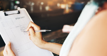 Person, hands and writing with clipboard at cafe for stock sheet, checklist or inventory at restaurant. Closeup, small business owner or manager with inspection for catering products at coffee shopの写真素材
