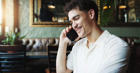 Happy man, conversation and talking with phone call at cafe for friendly discussion or chat. Male person, freelancer or customer with smile on mobile smartphone for contact or review at restaurantの写真素材
