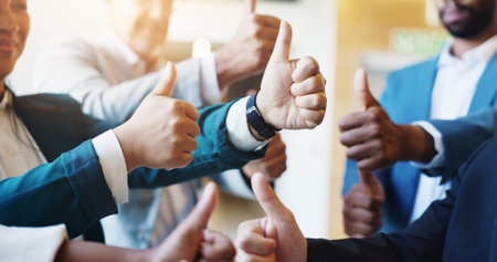 Business people, agreement and group in office, thumbs up and partnership for financial merger. Accounting, closeup and employees with hand gesture, cooperation and like with emoji, icon and feedbackの写真素材