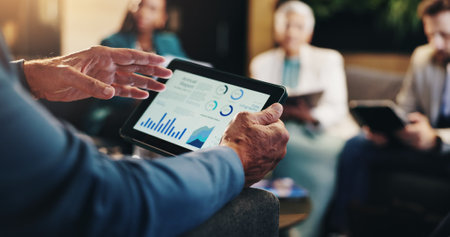 Business charts, hands and meeting with tablet screen for revenue stats, company performance and financial growth. Closeup, investors and graphs for budget forecasting, data analysis or profit reportの写真素材