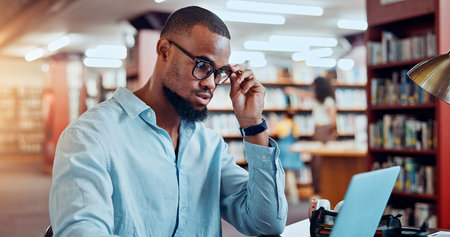 Student, laptop and black man in library, thinking and education with research for assignment....
