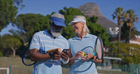 Laugh, phone and tennis with couple on outdoor court together for bonding, hobby or sports. App, fitness or mature with interracial man and woman at venue for exercise, leisure or love in summerの写真素材