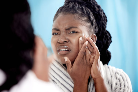 Mirror, acne problem and black woman in bathroom for with beauty crisis, morning routine and check skin health. Gen z girl, hands and blackhead on face with dermatology and upset for hormonal pimpleの写真素材