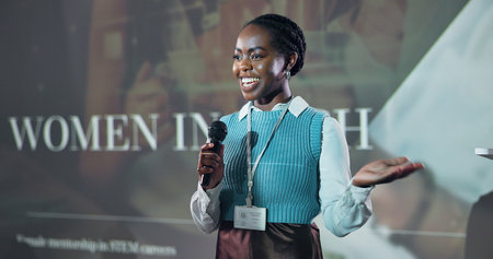 Business, speech and happy black woman at conference with mic for motivation at tech seminar. Keynote speaker, convention and presentation at event for advice, empowerment or equality with programmerの写真素材
