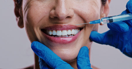 Woman, skincare and injection in studio for lip filler, relax and antiaging treatment. Mature model,...