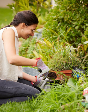 Gardening, spring and woman with flowers in backyard for natural environment, growth and ecosystem. Nature, gardener and person planting seeds, trees and plants for sustainability and agricultureの写真素材