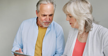 Tablet, information and senior couple talking together in studio on white background for research....