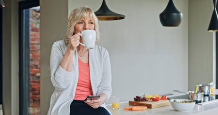 Woman, drinking coffee and phone or relaxing in kitchen, funny online conversation and social media....