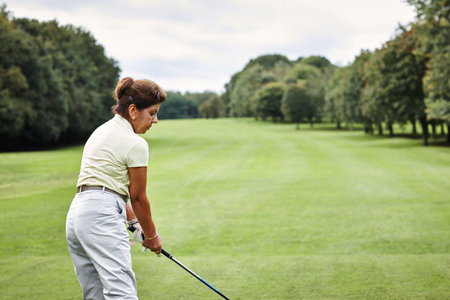 Golf, grass and woman at sports club for game, leisure and playing weekend hobby in nature. Hit, course and mature person on green lawn for competition, outdoor challenge and female golfer on field.の写真素材