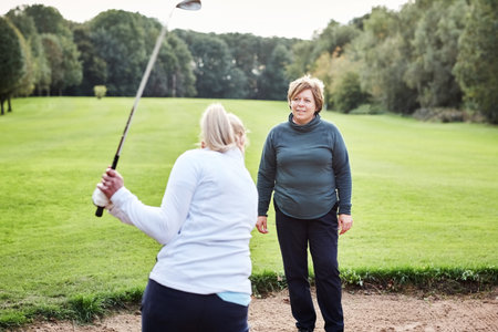 Sports, swing and women in sand for golf with coach for game, match and practice on golfing course. Fitness, exercise and people in bunker with sports club for training, competition and playingの写真素材