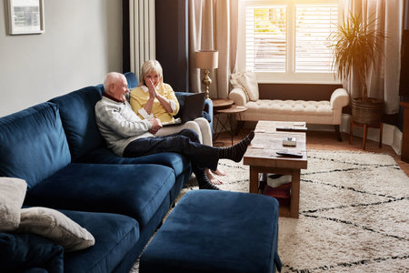 Laptop, relax and retirement with a senior couple on a sofa in the living room of their home for entertainment. Computer, video or happy with an elderly man and woman streaming in their apartmentの写真素材