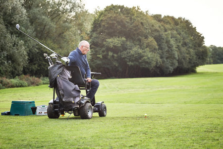 Golf, swing and man in wheelchair playing game on grass for hobby, retirement or exercise. Morning, sports and mature person with disability on course to tee off for competition, club or workout.の写真素材