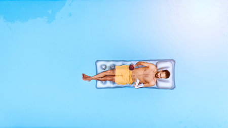 Reading, relax and man on inflatable in swimming pool for summer vacation, weekend break or getaway...
