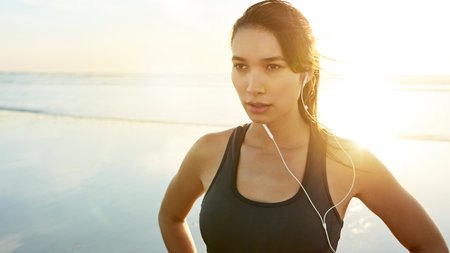Exercise, beach and thinking with woman ready for running, workout and summer with music. Athlete, sunrise or prepare to start jog for training, endurance or health for cardio wellness or marathonの写真素材