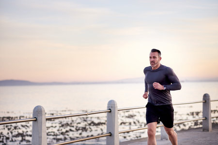 Ocean, running and man with energy, cardio and wellness with workout, exercise and routine. Person,...