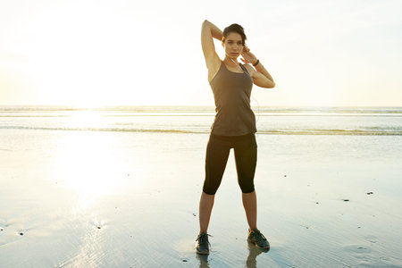 Girl, stretching and earphones by ocean, sunset and ready for training in summer with streaming....