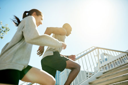 Fitness, friends and running in city for health, body wellness and training in low angle. Team, cardio and people exercise outdoor on steps for workout, sport and race with energy for performanceの写真素材