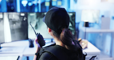 Control room, surveillance and woman with radio, watching and back of security guard, night or footage. Observation, camera and person with tech for communication, law enforcement or safety with cctvの写真素材