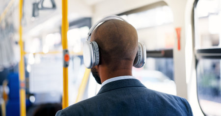 Bus, travel and man with headphones, music and commuting to work in morning, listening or audio. Back, employee and person with tech for playlist, sound and passenger with radio for trip or streamingの写真素材