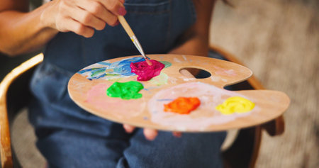 Person, hands and artist with paint palette for colorful art, design or creativity at home. Closeup, painter or designer with brush, tray or color mix for drawing skill, blending talent or artworkの写真素材