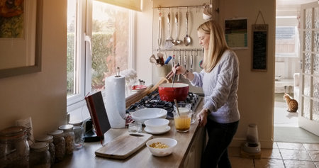 Woman, diet and cooking in kitchen, food and nutrition or prepare ingredients at home. Female person, process and relax or gourmet skills, wellness and vision for healthy meal, stirring and potの写真素材