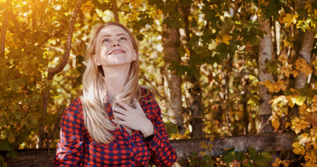 Outdoor, thinking and woman with a smile, break and wellness with happiness, relax and cheerful. Autumn, forest and woods with girl, lens flare and nature with environment, trees and ideas with joyの写真素材