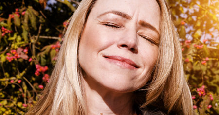 Happy, nature and mature woman in sunshine by the trees in outdoor park, field or garden. Freedom,...