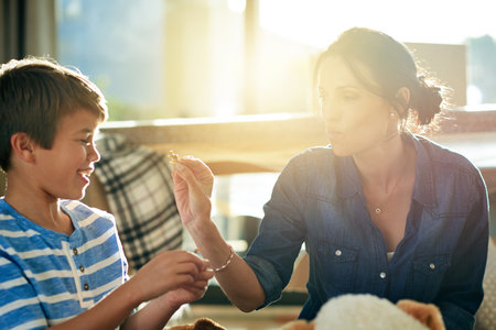 Child development, mother and son playing with toy cat in home together for growth or learning. Lens flare, motor skills and smile with woman teaching happy boy in apartment for animal educationの写真素材