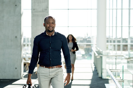 Black man, walking and start of work in office, travel and financial advisor with bag for arrival. Male person, company convention and suitcase journey to seminar, commute and leaving workplaceの写真素材
