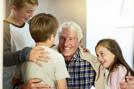 Hug, love or smile with grandpa and kids in home together for bonding, relationship or visit. Family, happy and retirement with senior man talking to grandchildren in apartment or developmentの写真素材