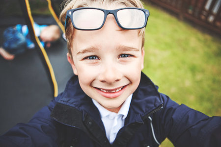 Fun, playful and happy boy playing in home garden, backyard or park playground. Portrait, closeup and headshot or face of adorable, cute or little child having fun, enjoying break and taking a selfieの写真素材
