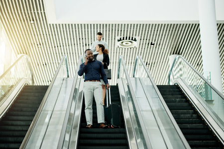 Man, phone call and suitcase at escalator for travel, business contact or booking accommodation. Below, journalist and luggage in airport for source lead, information update or planning trip for newsの写真素材