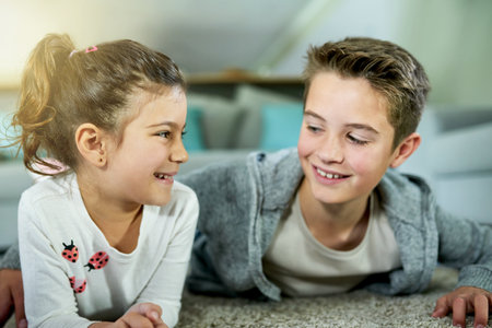 Family, siblings and happy on home floor, love and together for childhood security. Conversation, children smile and living room carpet to relax for trust, support and relationship bonding to connectの写真素材