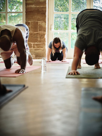 Yoga class, fitness and people stretching for exercise, workout and wellness with peace, calm and balance. Group on floor in cat cow to downward facing dog pose for pilates, studio training or healthの写真素材