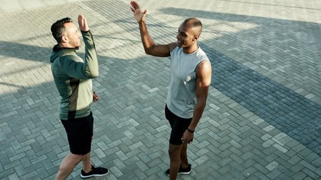 High five, smile and celebration for friends, workout and personal trainer with motivation for client. Outdoor, above and people with gesture for accomplishment, thank you and success for fitnessの写真素材