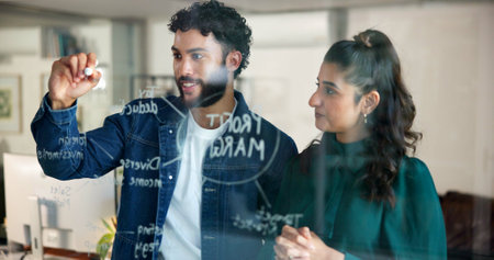 Man, writing and brainstorming by glass for team project strategy, profit margin or budget for marketing. People, collaboration and mind map with information, vision or research for sales projectionの写真素材