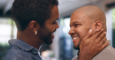 Gay couple, happy and smile in house for love, flirting and relationship in living room or lounge. Dating, touch and LGBTQ partner with commitment, trust and relax together for weekend and romanceの写真素材