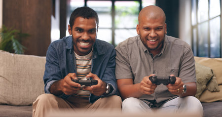 Home, friends and gaming with controller on sofa for multiplayer, competition and entertainment. Happy, people and men with smile in living room for esports challenge, streaming and playful contestの写真素材