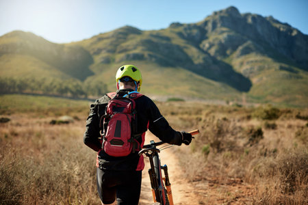 Man, tired and walking on mountain with bike, journey and travel with flat tire on trail. Back, athlete and bicycle on nature path for explore track, backpacking adventure and exercise in Australiaの写真素材