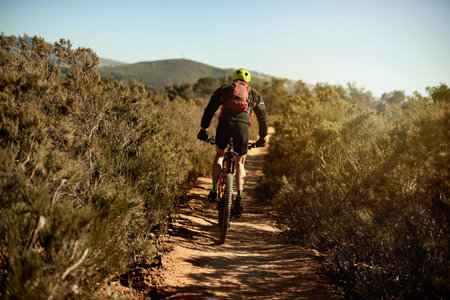 Mountain bike, cycling and back of athlete with sports race, workout or cardio exercise on dirt...