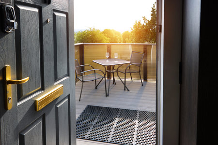 Modern, balcony and door at hotel with chairs, table and wine glass outdoors at sunrise sky....