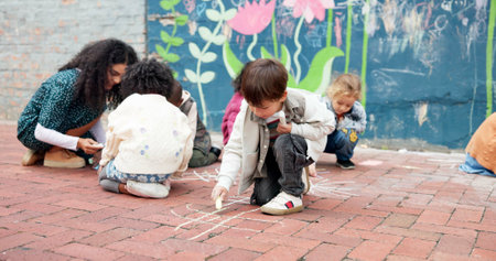 Kindergarten school, children and drawing with chalk on floor or playground for fun outdoor activity. Kids, group or creative youth with teacher for art, game or childhood development at elementaryの写真素材