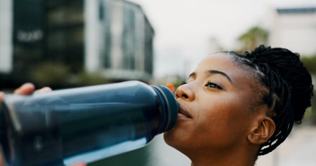 Black woman, drinking water and hydration outdoor for health, wellness and electrolyte liquid with...