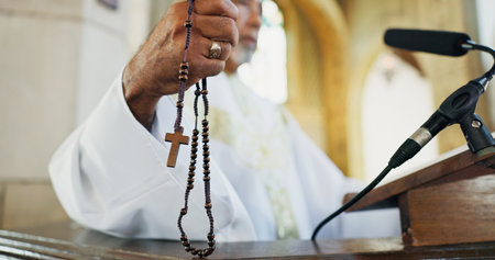 Rosary, hand and preacher praying in church as Christian for salvation, service and worship with faith. Religion, bishop and respect with man or praise for guidance, speech and spiritual ceremonyの写真素材
