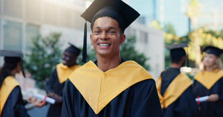 Happy, man and portrait of graduate in city for education goal, qualification or achievement. Smile, outdoor and male university student with pride for college degree with learning at campus in town.の写真素材