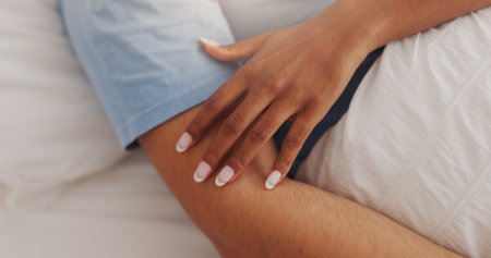 Hands, touch and couple rest on bed for intimacy, partner affection and connection in morning. Closeup, people and sleeping with embrace for care, romance and bonding for marriage commitment at houseの写真素材