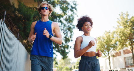 Couple, exercise and running for workout in city, cardio together with fitness and wellness. Below interracial people, training or sports challenge with team, urban and athlete partners outdoorの写真素材